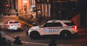 Two police vehicles parked on a city street at night under streetlights